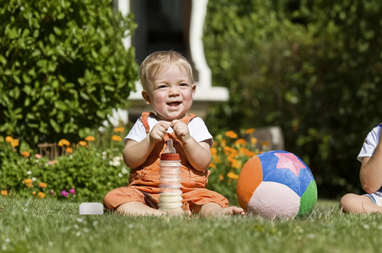 Un jeune enfant assis dans l’herbe, un biberon BIBEON déplié posé devant lui